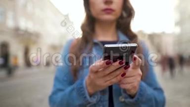 日落时分，女人用智能手机走在老街上。 专注于智能手机。 通信、社交网络、在线